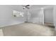 Spacious living room with plush carpeting, ceiling fan, and an open layout with bright, neutral decor at 6412 Sullins Rd, Charlotte, NC 28214