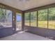 Enclosed sunroom featuring large windows offering backyard views and access to outdoors at 6921 Idlewild Rd, Charlotte, NC 28212