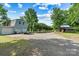 A large three-door garage sits on a gravel lot with mature trees and additional wooden shed at 6992 Sherrills Ford Rd, Sherrills Ford, NC 28673