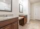 Bathroom featuring double sinks with granite countertops, wooden cabinets, decorative mirrors, and neutral tiling at 805 Old Little Rock Rd, Charlotte, NC 28214