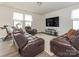 Cozy living room with leather seating, a large TV, natural light, and exercise equipment on a hardwood floor at 805 Old Little Rock Rd, Charlotte, NC 28214