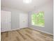 Bedroom with wood-look flooring, double-door closet, and large window at 8611 Earthenware Dr, Charlotte, NC 28269