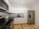 Stylish kitchen boasts stainless steel appliances, ample storage in white cabinetry, and wood-look floors at 8611 Earthenware Dr, Charlotte, NC 28269