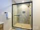 Walk-in shower showcasing tile surround, a shower niche, and glass doors at 8611 Earthenware Dr, Charlotte, NC 28269