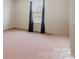 Virtually staged bedroom with plush carpeting and a window dressed with dark curtains at 10211 Snowbell Ct, Charlotte, NC 28215