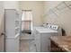 Functional laundry room featuring modern appliances, tile floors, and ample shelving at 10211 Snowbell Ct, Charlotte, NC 28215