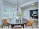 Chic dining area with a round table and stylish chairs, illuminated by a modern chandelier and natural light from large windows at 1025 Harrogate Dr, Bessemer City, NC 28016
