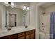 Bathroom vanity with double sinks and storage with a shower and tub in the background at 11718 Preservation Ln, Charlotte, NC 28278