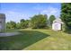 Spacious backyard featuring a concrete patio, a storage shed, mature trees, and a lush green lawn at 1457 Matthew Allen Cir, Kannapolis, NC 28081