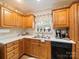 Functional kitchen featuring wood cabinets, white countertops, stainless steel sink, and a window with floral accents at 1505 Moss Springs Rd, Albemarle, NC 28001