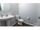 Modern powder room featuring a pedestal sink, round mirror, and wood-look flooring at 177 Willow Valley Dr, Mooresville, NC 28115
