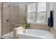 Bright bathroom with a tiled glass-enclosed shower and a separate soaking tub near frosted windows at 2021 Pinyon Ln, Lancaster, SC 29720