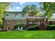 Rear exterior view of the home featuring a brick facade, multiple windows, a deck, and a spacious, well-maintained yard at 2025 Sagamore Rd, Charlotte, NC 28209