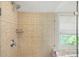 Glass shower with tan tiles and a view of the landscaped yard outside of the window at 2025 Sagamore Rd, Charlotte, NC 28209