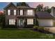 Two-story home featuring black shutters, an American flag, a well-manicured lawn, and a two-car garage at 204 Pebble Creek Xing, Fort Mill, SC 29715