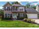 Two-story home featuring black shutters, an American flag, a well-manicured lawn, and a two-car garage at 204 Pebble Creek Xing, Fort Mill, SC 29715