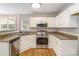 Bright kitchen features stainless steel appliances, granite countertops, white cabinetry, and wood-look floors at 204 Pebble Creek Xing, Fort Mill, SC 29715