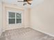 A cozy bedroom with plush carpet, a ceiling fan, and bright natural light from the window at 2324 Bonterra Blvd, Indian Trail, NC 28079
