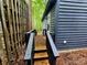 Side entryway with wooden steps and railing, complemented by dark wood siding at 2800 Patio Ln, Gastonia, NC 28056