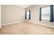 Empty carpeted bedroom with light-colored walls, two windows with blue curtains providing natural light at 309 N Aspen St, Lincolnton, NC 28092
