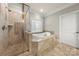 Elegant bathroom featuring a glass-enclosed shower and a luxurious soaking tub with decorative window at 310 Ridge Reserve Dr, Clover, SC 29710