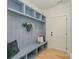 Light and airy mudroom boasts blue-gray millwork, shelves, bench, and wooden flooring at 3478 Winters St, Newton, NC 28658