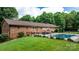 A backyard featuring a brick home, outdoor dining, black fencing, and a refreshing in-ground pool at 4916 Leepers Creek Rd, Maiden, NC 28650