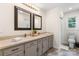 A bathroom featuring double sinks, framed mirrors, and gray cabinets, complemented by natural light at 4916 Leepers Creek Rd, Maiden, NC 28650