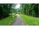 Scenic driveway leading to a charming brick home framed by lush greenery and mature trees at 4916 Leepers Creek Rd, Maiden, NC 28650