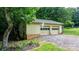 Detached two-car garage with beige doors surrounded by lush greenery and stone landscaping at 4916 Leepers Creek Rd, Maiden, NC 28650