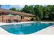 A beautiful in-ground pool with ample seating and outdoor dining beside a red brick home at 4916 Leepers Creek Rd, Maiden, NC 28650