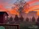 Backyard view with a storage shed, garden and lawn surrounded by lush trees against a striking sunset sky at 509 Brawley Rd # 7, Cleveland, NC 27013