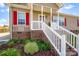 Close-up of front porch featuring white railing, brick foundation, and landscaped flower bed at 509 Brawley Rd # 7, Cleveland, NC 27013
