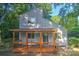 Charming two-story home with a covered wooden porch surrounded by lush trees at 5995 Tall Tree Ln, Harrisburg, NC 28075