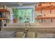 Modern kitchen with granite countertops, stainless steel sink, and open shelving with greenery at 5995 Tall Tree Ln, Harrisburg, NC 28075