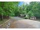 View of a long driveway, carport, storage shed, and brick retaining wall with trees and greenery at 6227 Dogwood Ln, Waxhaw, NC 28173
