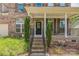 Inviting front porch with brick steps and wrought iron railing, surrounded by lush greenery at 8336 Early Bird Way, Mint Hill, NC 28227