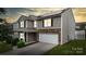 Charming two-story home with a stone-accented garage and manicured lawn at dusk at 8511 Redding Glen Ave, Charlotte, NC 28216