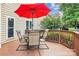 Enjoy outdoor dining on this wooden deck featuring a table, chairs, and a vibrant red umbrella for shade at 8612 Tintinhull Ln, Waxhaw, NC 28173