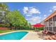 Relaxing backyard features a sparkling pool, patio seating with a red umbrella, and lush green landscaping at 8612 Tintinhull Ln, Waxhaw, NC 28173