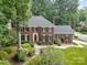 Stunning brick home featuring mature trees, lush landscaping, a chimney, and a classic facade at 8700 Thornbury Ln, Huntersville, NC 28078