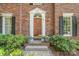 Elegant entryway featuring a wood door, sidelights, decorative lighting, and manicured landscaping at 8700 Thornbury Ln, Huntersville, NC 28078