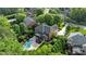 Aerial view of an estate featuring a pool, fire pit, manicured lawn, and lush landscaping and mature trees at 9021 Unbridle Ln, Waxhaw, NC 28173
