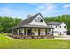 Charming white farmhouse with a sprawling front porch and black accents, surrounded by a lush green lawn at 930 Hawley Rd, McConnells, SC 29726