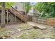 Landscaped backyard with deck access stairs, stone retaining wall, small bridge, and a mix of wood and wrought iron fencing at 9437 Macquarie Ln, Charlotte, NC 28227