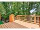 View of a backyard deck surrounded by lush trees, fencing, and a house in the background at 9437 Macquarie Ln, Charlotte, NC 28227