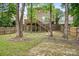 Spacious backyard featuring a deck with wooden stairs, brick pathway, mature trees, and partial fencing at 9437 Macquarie Ln, Charlotte, NC 28227