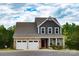 Charming two-story home featuring a stone facade, gray siding, two-car garage, and landscaped front yard at 10100 Jack Nicklaus Dr, Lancaster, SC 29720