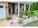 Inviting front porch with stone pillars, a red door, decorative landscaping and an address plaque at 10100 Jack Nicklaus Dr, Lancaster, SC 29720