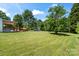 Expansive backyard with lush green grass, mature trees, and a covered patio area, perfect for outdoor living at 1015 4Th St, Spencer, NC 28159